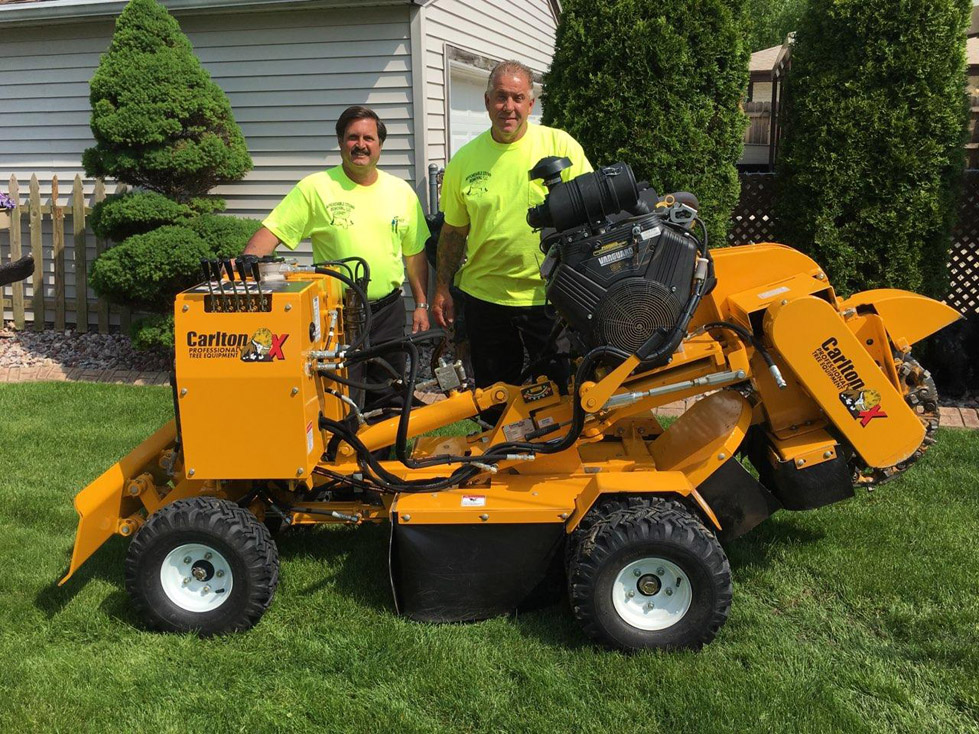 Owners Eric Christensen and Tim Duerr standing by stump removal equipment